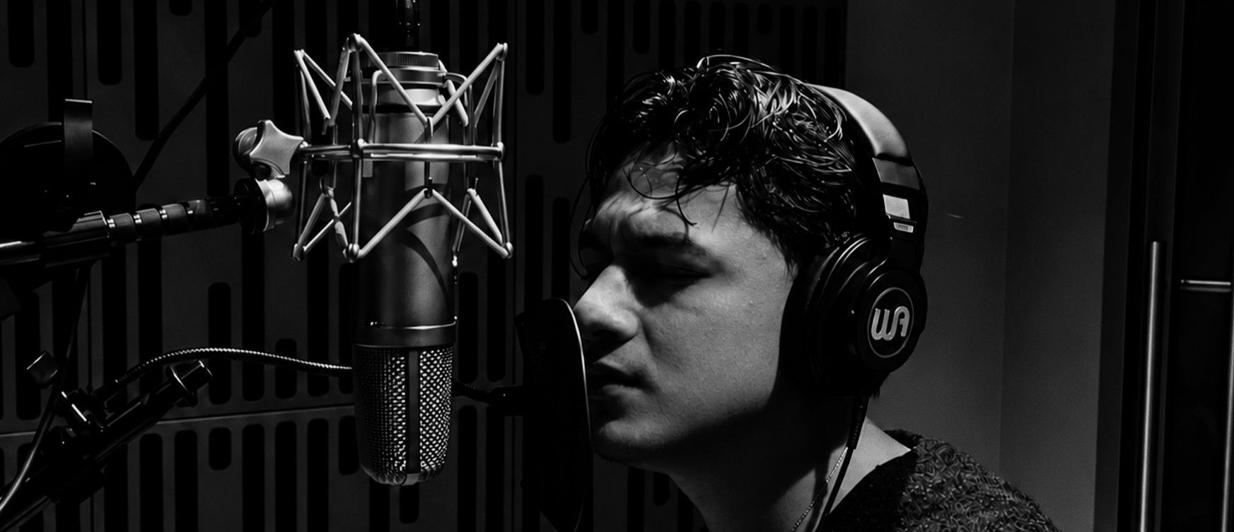Diego singing into a studio microphone, eyes closed, headphones on
